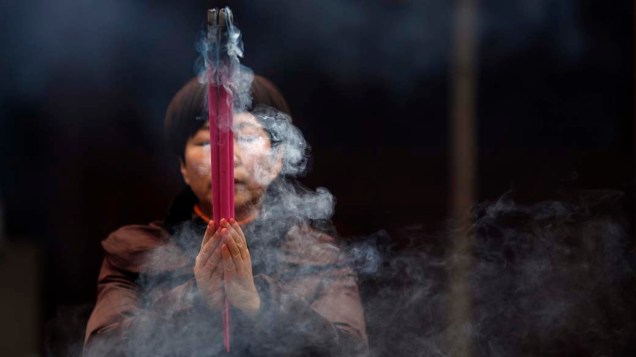 Mulher segura incensos durante as comemorações prévias do Ano Novo Lunar em Shangai, China