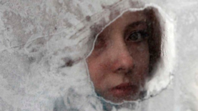 Mulher olha por janela de taxi coberta por camada de gelo em Kiev, Ucrânia