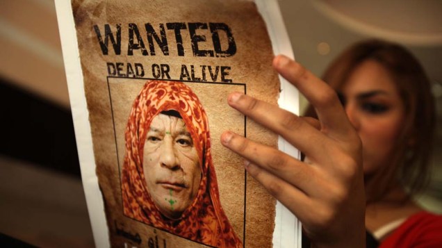 Em Trípoli, mulher com o jornal Arus al-Bahr, com imagem de Kadafi vestido com traje tradicional feminino