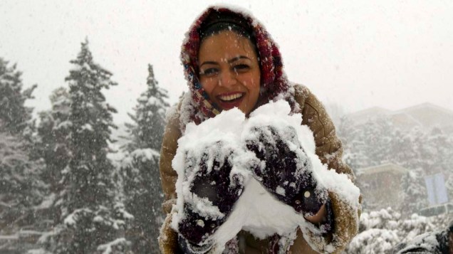 No Irã, mulher recolhe neve durante nevasca