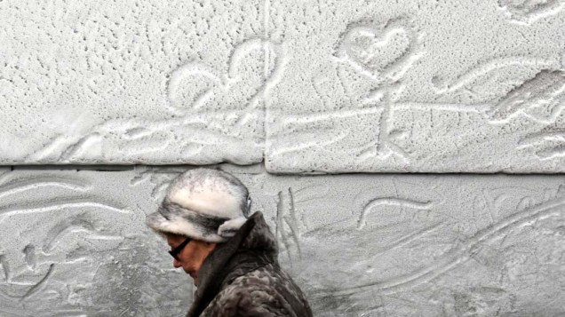 Mulher caminha por muro coberto de neve na cidade de São Petersburgo, Rússia