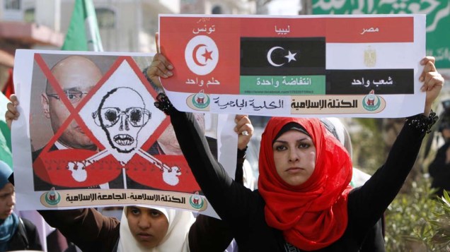Mulher palestina carrega placa com as bandeiras da Líbia, Tunísia e Egito em protesto contra o presidente libanês Muamar Kadafi na cidade de Gaza