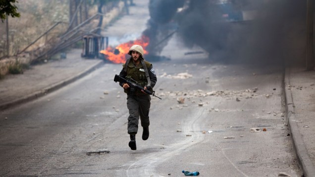 Soldado israelense corre durante confrontos com palestinos, no início das celebrações do Nakba, em Jerusalém - 13/05/2011