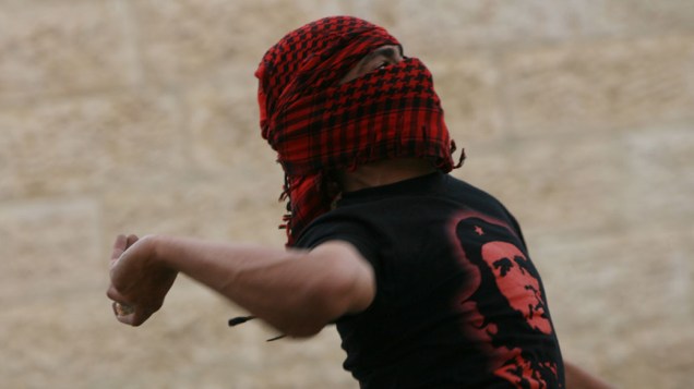 Jovem mascarado atira pedras em soldados israelenses durante os confrontos que marcaram as celebrações do Nakba, em Israel - 15/05/2011