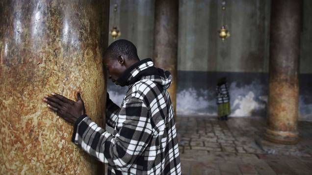 Fiel faz oração nas colunas de mármore da Igreja da Natividade, reverenciada pelos cristãos como local de nascimento de Jesus, em Belém
