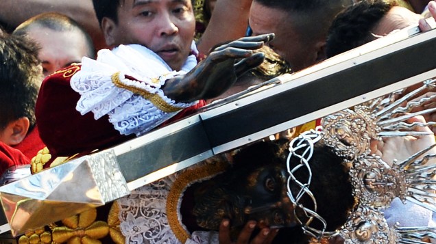 Católicos filipinos sobem em carro para tentar tocar a imagem do Nazareno Negro, nesta quinta-feira (9), em Manila