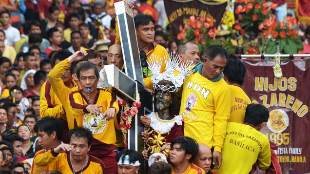 Católicos filipinos sobem em carro para tentar tocar a imagem do Nazareno Negro, nesta quinta-feira (9), em Manila