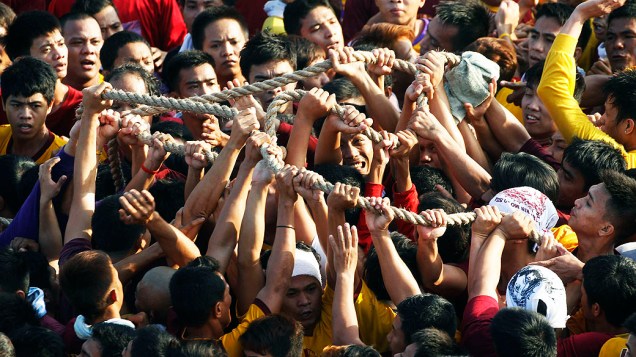 Católicos filipinos sobem em carro para tentar tocar a imagem do Nazareno Negro, nesta quinta-feira (9), em Manila