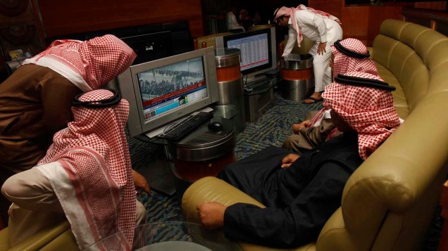 Investidores sauditas assistem noticiário sobre a situação do Egito na cidade de Riad