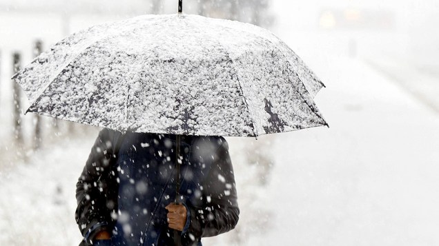 Uma mulher se protege da neve com um guarda chuva, devido as nevascas na região da Cantábria que se encontra em alerta laranja, pela neve que pode acumular muitos centímetros, na Espanha