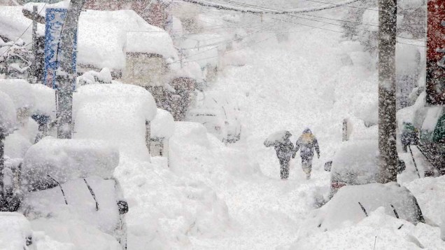 Casal caminha por rua coberta de neve na cidade de Gangneung, Coreia do Sul