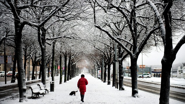 Mulher passeia por rua coberta de neve, na Suécia