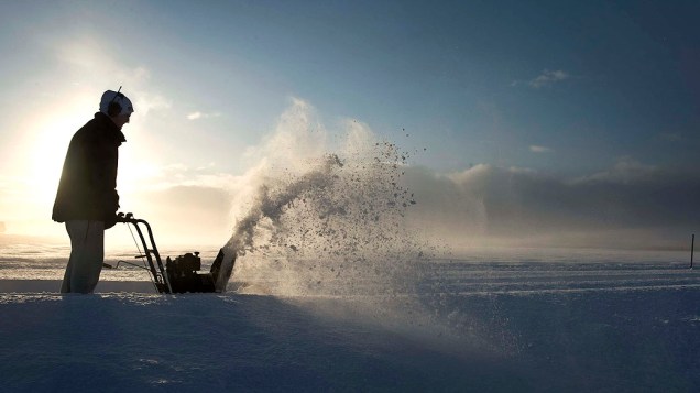 Homem limpando estrada coberta por neve, na Suécia