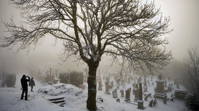 Homens andam em cemitério coberto por neve, na Escócia