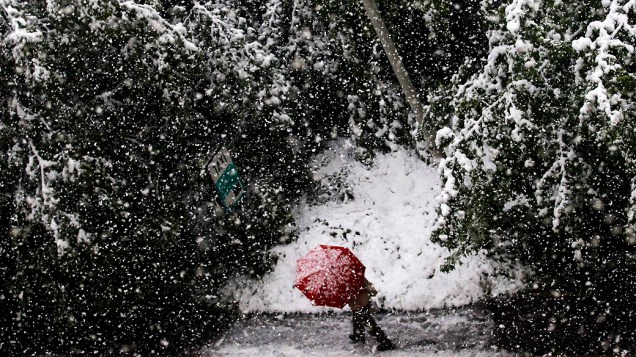 Homem caminha segurando um guarda-chuva no centro de Sarajevo, depois de uma forte nevasca que atingiu a capital da Bósnia