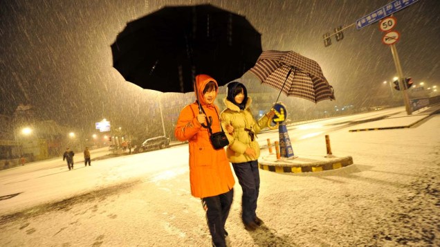 Mulheres caminham em rua coberta de neve na cidade de Jinan, China