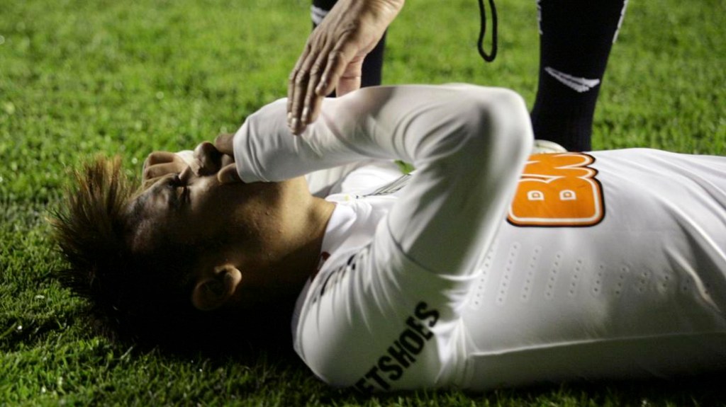 Neymar, do Santos, caído no gramado após ser atingido por objetos jogados pela torcida do Bolívar, em La Paz, no jogo de ida das oitavas de final da Libertadores 2012