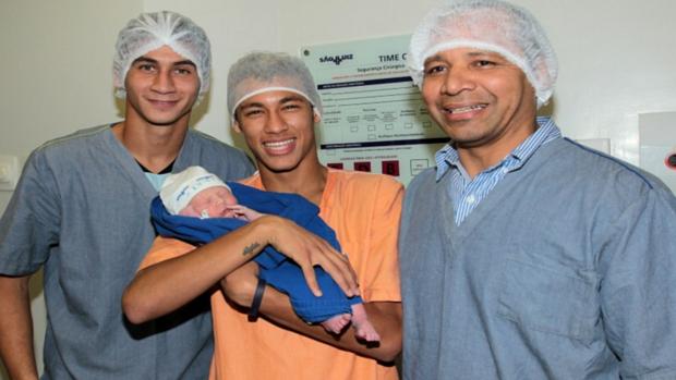 Neymar segura o filho Davi Lucca entre Paulo Henrique Ganso (à esq) e seu pai