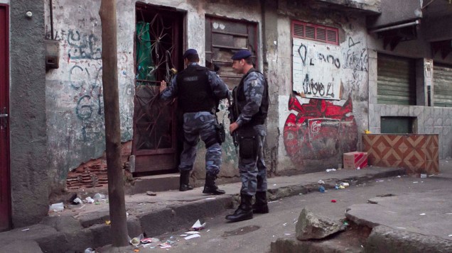 Policiais revistam casa com símbolos de facções criminosas, durante ocupação do Morro da Mangueira, no Rio de Janeiro - 19/06/2011