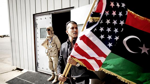 Oficial líbio leva a bandeira de seu país junto à dos Estados Unidos