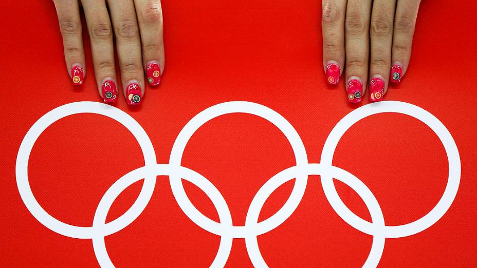 Voluntária é fotografada ao lado dos anéis olímpicos durante 5.000 metros da patinação de velocidade nos Jogos de Inverno de Sochi, na Rússia, nesta quarta-feira (19)