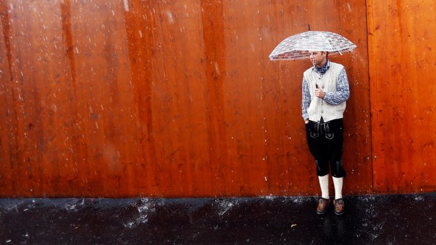 Visitante se protege da forte chuva durante a 179ª Oktoberfest, em Munique, Alemanha