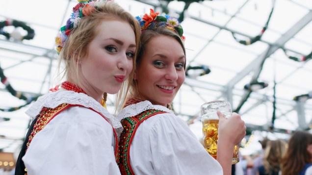 Garotas polonesas, vestidas com traje tradicional polaco bebem cerveja depois de participar do desfile de abertura da Oktoberfest