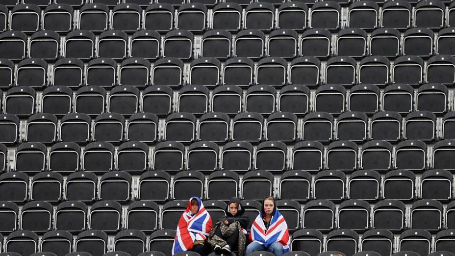 Espectadores sentam-se sob a chuva nas arquibancadas do Greenwich Park em Londres, antes da competição de saltos de obstáculos 