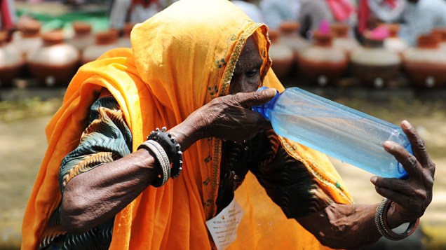 Mulher bebe água em dia quente de verão em Nova Délhi, Índia