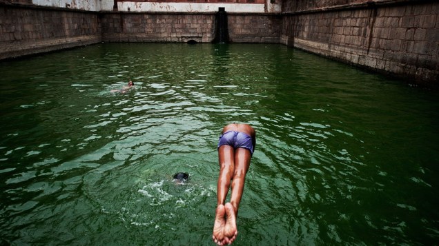 Menino mergulha em um reservatório de água, conhecido como baoli, em Nizamuddin Dargah, Nova Délhi