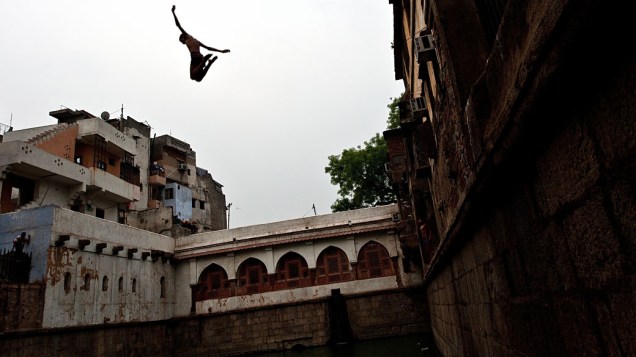 Menino salta para mergulho em um reservatório de água, conhecido como baoli, em Nizamuddin Dargah, Nova Délhi