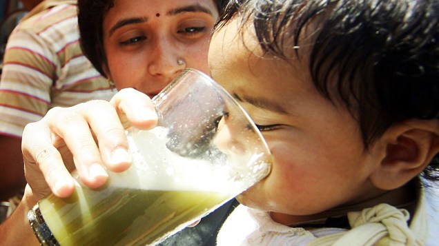 Bebê toma caldo-de-cana para se refrescar do calor em Jammu, Índia