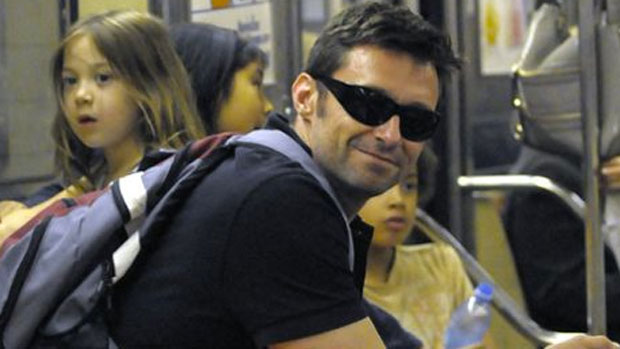 Hugh Jackman sorri para fã que o fotografa no metrô