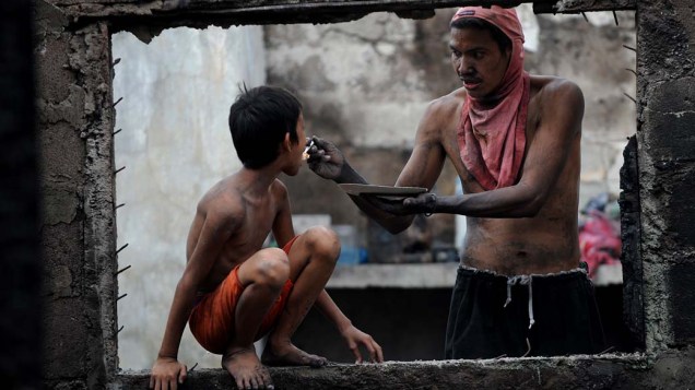 Pai alimenta filho após incêndio que atingiu mais de 80 casas em Manila, nas Filipinas