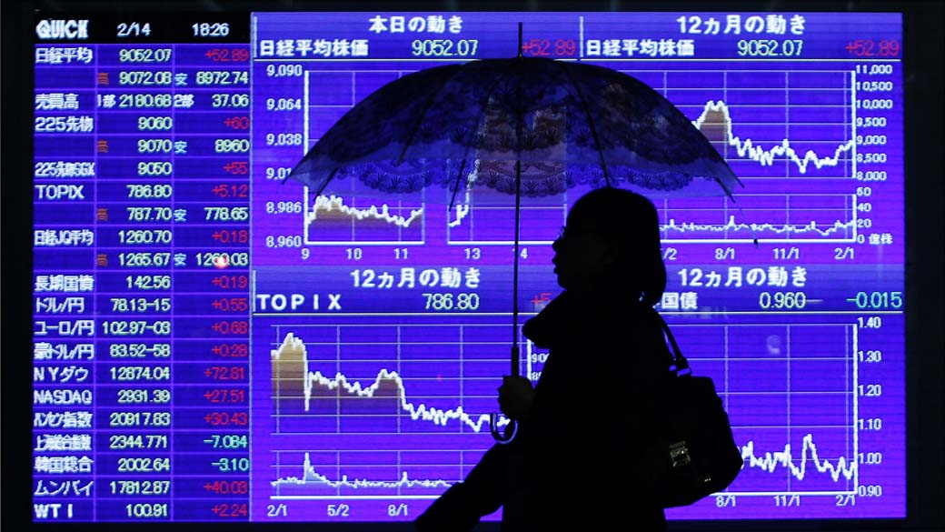 Mulher passa por painel de cotações em bolsa de valores de Tóquio, Japão