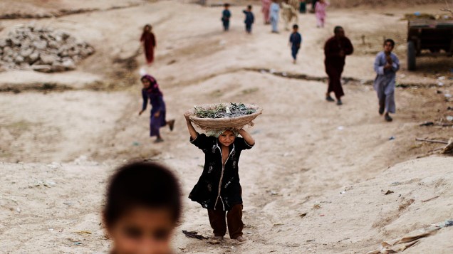 Menina afegã, volta para casa carregando uma cesta sobre a cabeça nos arredores de Islamabad, no Paquistão