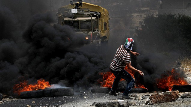 Manifestante palestino atira pedras em direção a soldados israelenses em Naplusa, na Cisjordânia