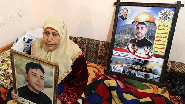 A mãe do prisioneiro palestino Ali Abu Fool carrega seu retrato enquanto espera sua libertação, em Gaza