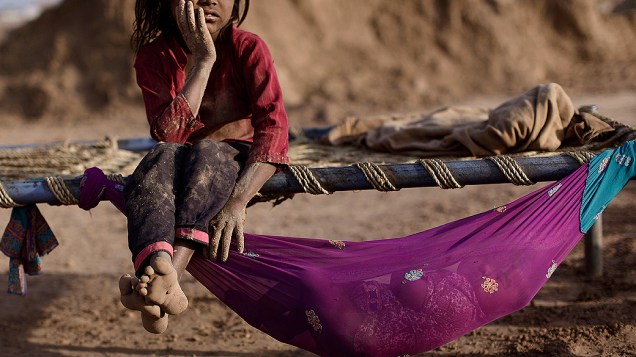 Criança paquistanesa, que trabalha em uma fábrica de tijolos, descansa em uma cama ao lado de sua irmã. O Dia Mundial Contra o Trabalho Infantil é comemorado nesta terça-feira