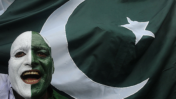 Paquistanês com o rosto pintado com as cores do país celebra com a bandeira do Paquistão os 65 anos da independência do país, em Wagah