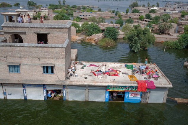 Vítimas das enchentes no Paquistão sobem nos telhados para receber alimentos do exército local em Khairpur Nathan Shah.