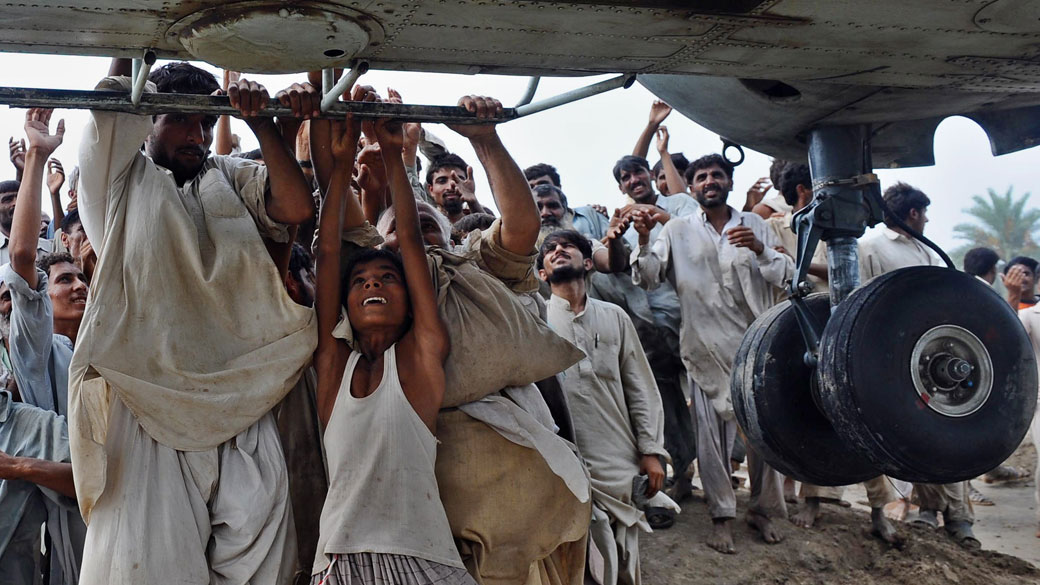Sobreviventes das enchentes tentam subir em helicóptero do exército que distribuía comida em Lal Pir, Paquistão
