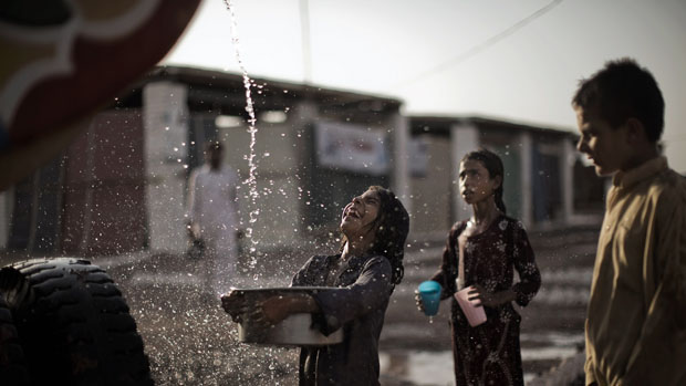 Menina paquistanesa afetada pelas chuvas enche sua bacia com água potável distribuída por um caminhão
