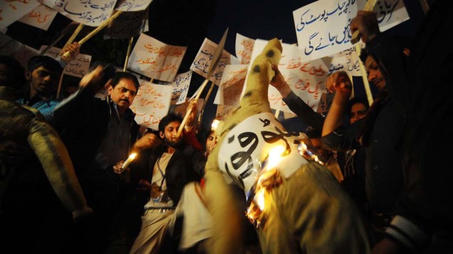 Ativistas colocam fogo em boneco representando a Otan durante protesto contra ataques ao Paquistão, em Lahore