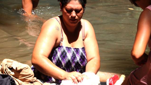 Mulher lava roupas em rio, em Ñacunday, no Paraguai
