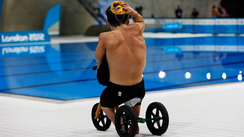 O atleta australiano Grant Patterson se dirige até a piscina do Centro Aquático utilizando uma bicicleta