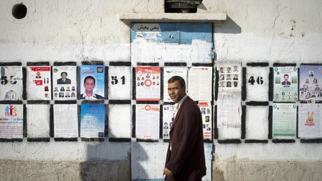 Homem passa por cartazes de candidatos para a eleição do dia 23 em Tunis, na Tunísia