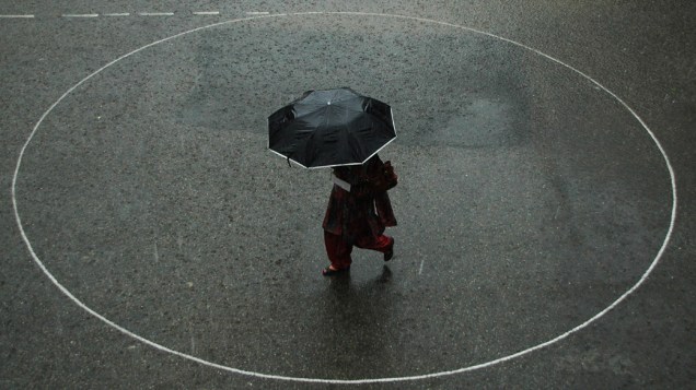 Pedestre com guarda-chuva em punho caminha por uma rua durante uma chuva de monção na cidade montanhosa do norte de Shimla, Índia