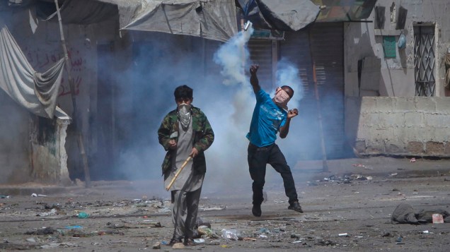 Manifestantes atiram cápsulas de gás lacrimogênio contra forças de segurança durante operação em Lyari região de Karachi, Paquistão