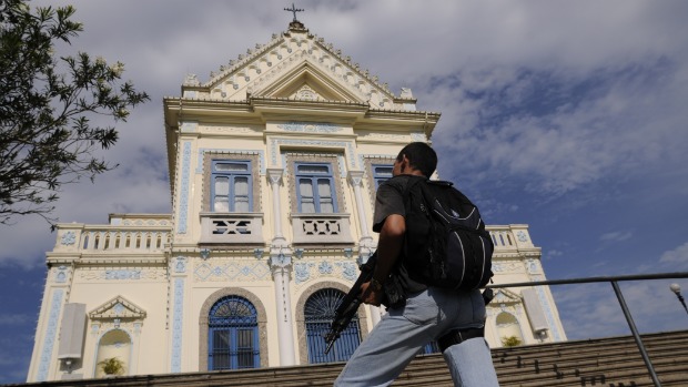 Policial de prontidão na Igreja da Penha, de onde se vê todo o bairro e o conjunto de favelas